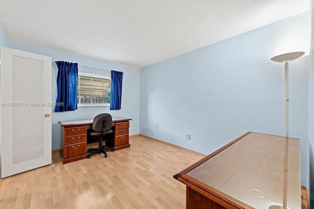 office space featuring baseboards, light wood-style floors, and a textured ceiling