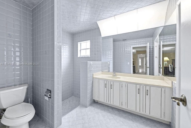 full bathroom with toilet, tile walls, a tile shower, and vanity