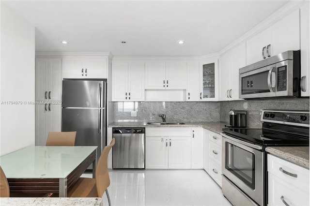 kitchen with stainless steel appliances, white cabinetry, a sink, and tasteful backsplash