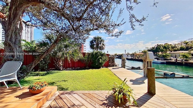 view of dock with a lawn, a water view, and fence