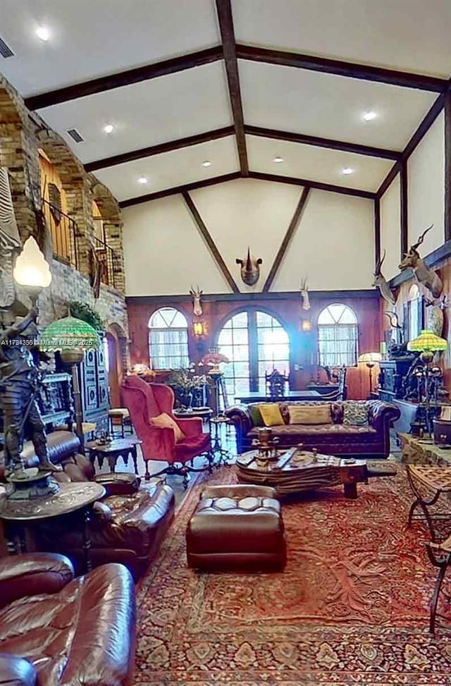 living area with high vaulted ceiling, visible vents, and beam ceiling