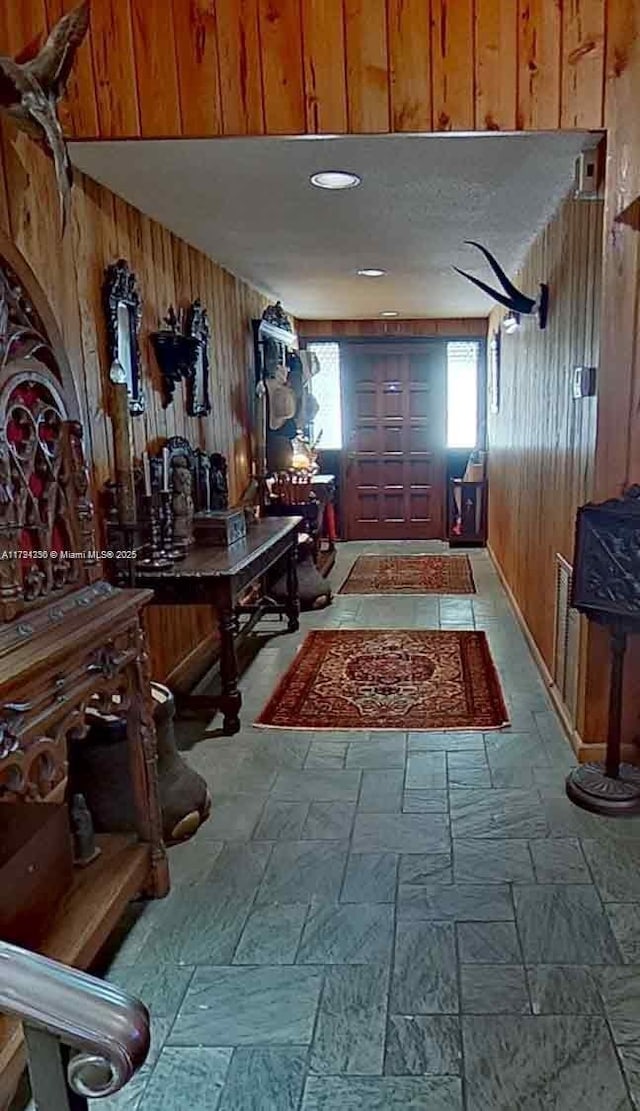 corridor with stone tile flooring and wooden walls