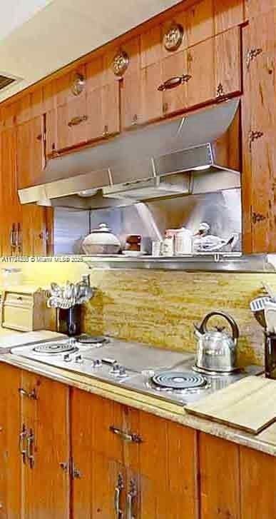 kitchen with light countertops, brown cabinetry, and electric stovetop