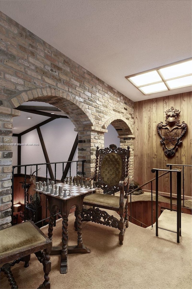 living area with carpet floors, arched walkways, and a textured ceiling