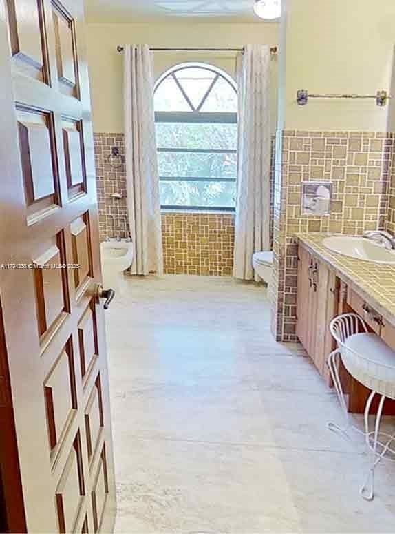 full bath with vanity, tile patterned flooring, toilet, tile walls, and a wainscoted wall