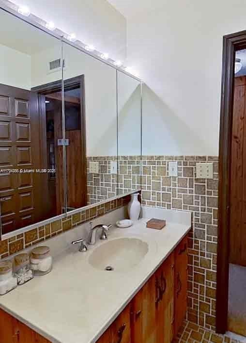 bathroom with vanity, a wainscoted wall, visible vents, and tile walls