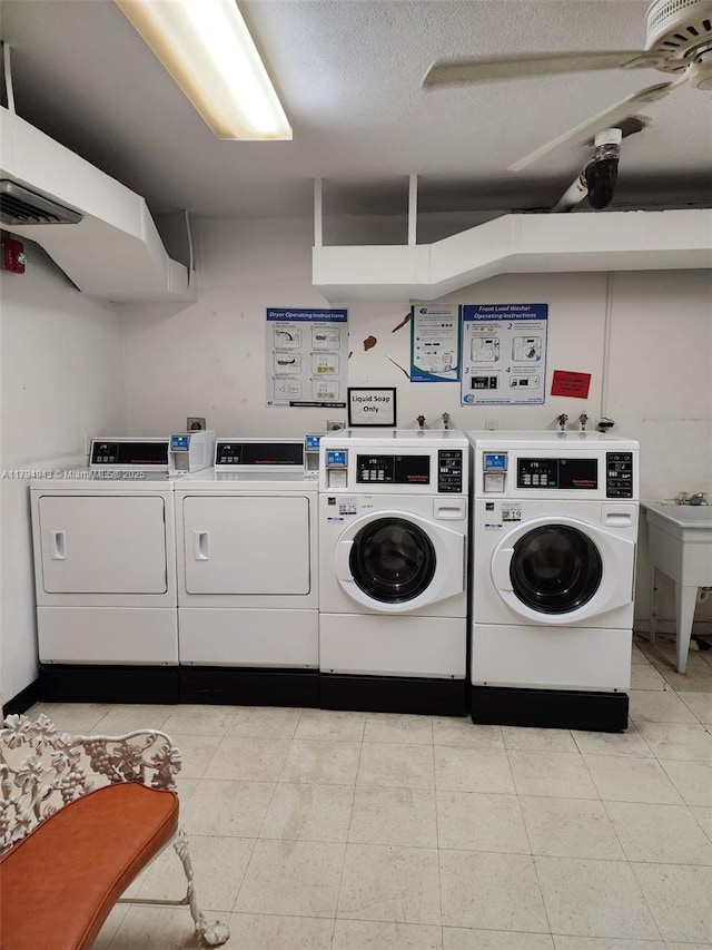 common laundry area featuring a sink, washer and clothes dryer, a textured ceiling, and light tile patterned floors