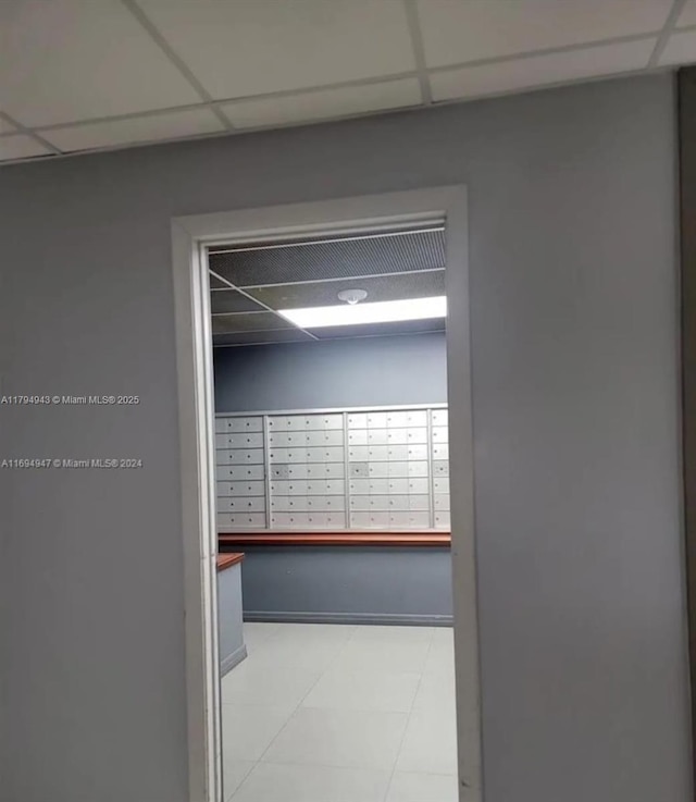 hall featuring a paneled ceiling and mail area