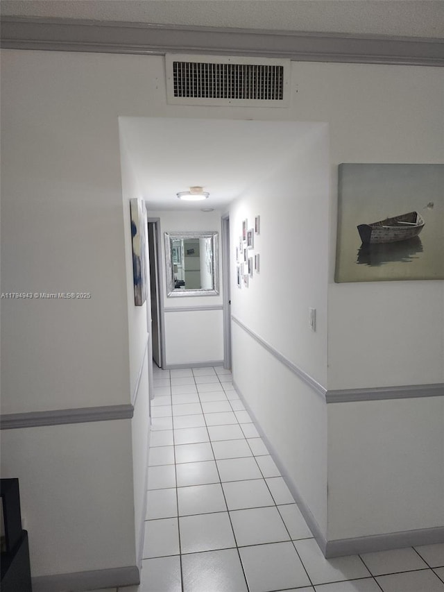 hallway with visible vents, baseboards, and light tile patterned flooring