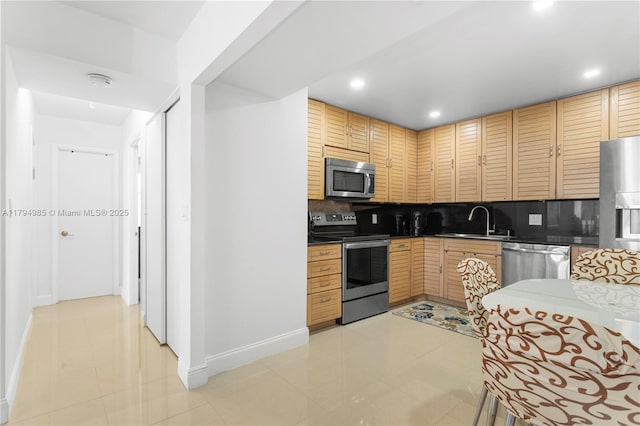 kitchen with backsplash, appliances with stainless steel finishes, a sink, baseboards, and recessed lighting