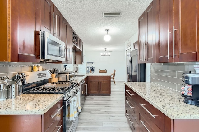4220 NW 114th Ave, Sunrise, FL 33323 - kitchen with visible vents, decorative backsplash, light stone countertops, light wood-style flooring, and appliances with stainless steel finishes