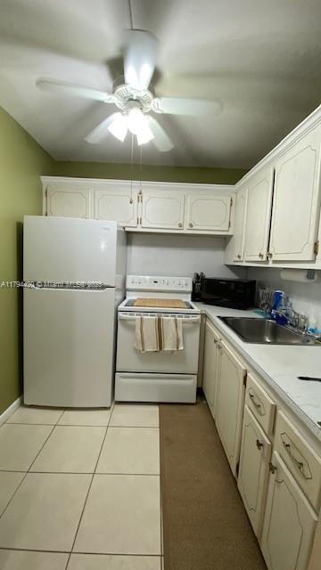 kitchen featuring electric range, black microwave, a sink, light tile patterned floors, and freestanding refrigerator