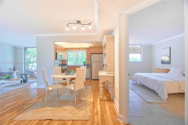 interior space with crown molding, freestanding refrigerator, light wood-style floors, and baseboards