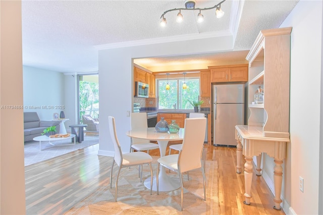 dining space with a textured ceiling, light wood finished floors, and a wealth of natural light