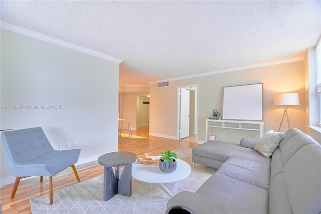 living area featuring crown molding, a textured ceiling, visible vents, and light wood finished floors