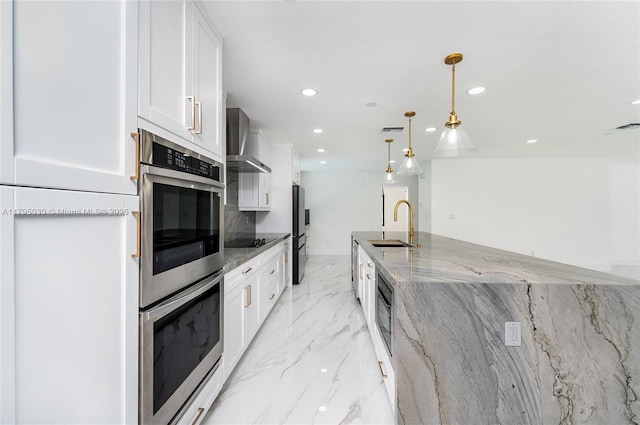 kitchen featuring wall chimney range hood, appliances with stainless steel finishes, a sink, marble finish floor, and white cabinetry