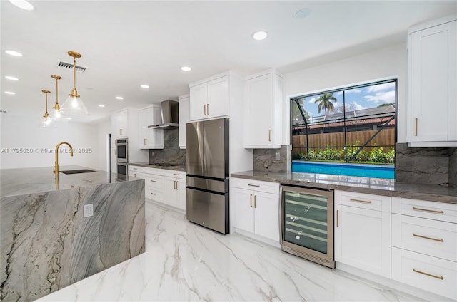 kitchen featuring marble finish floor, beverage cooler, wall chimney range hood, a sink, and stainless steel appliances