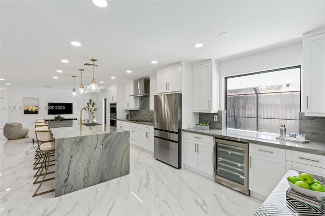 kitchen featuring backsplash, a sink, wine cooler, stainless steel appliances, and wall chimney exhaust hood