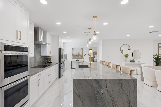 kitchen featuring backsplash, stainless steel double oven, black electric cooktop, recessed lighting, and wall chimney exhaust hood