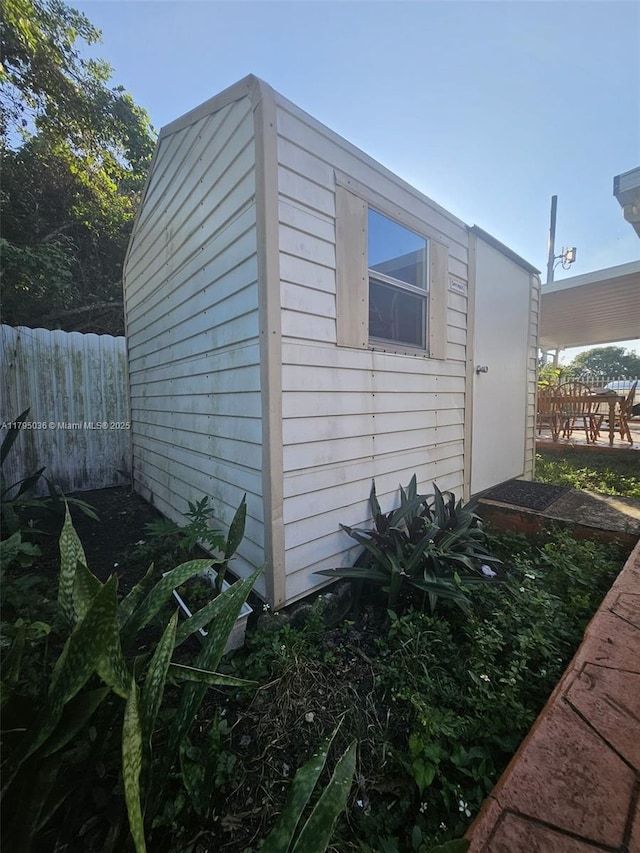 view of property exterior with fence and an outbuilding