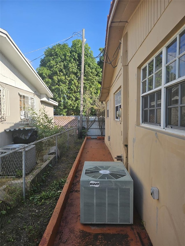 view of property exterior featuring central air condition unit, fence, and stucco siding