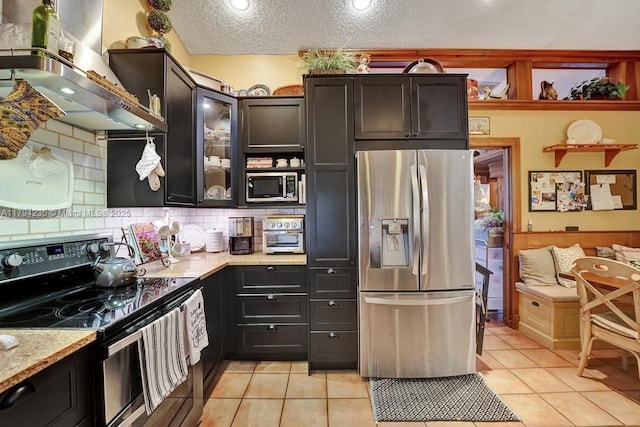9682 Ridgecrest Ct, Davie, FL 33328 - kitchen with appliances with stainless steel finishes, wall chimney range hood, light tile patterned flooring, decorative backsplash, and a textured ceiling