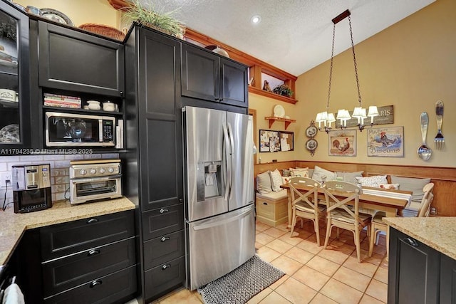 kitchen with light tile patterned floors, appliances with stainless steel finishes, dark cabinetry, and lofted ceiling