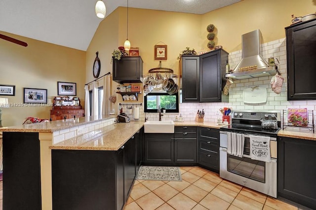kitchen with wall chimney range hood, range with two ovens, tasteful backsplash, a sink, and a peninsula