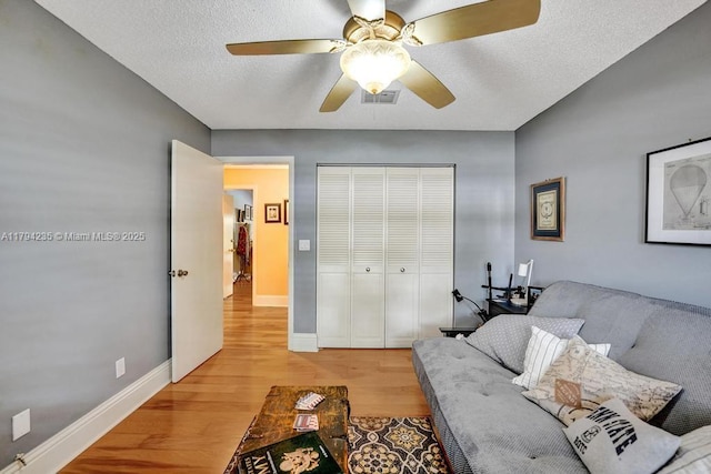 living room with visible vents, light wood-style floors, ceiling fan, and baseboards
