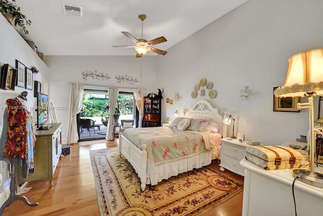 bedroom with a ceiling fan, visible vents, light wood finished floors, lofted ceiling, and access to outside