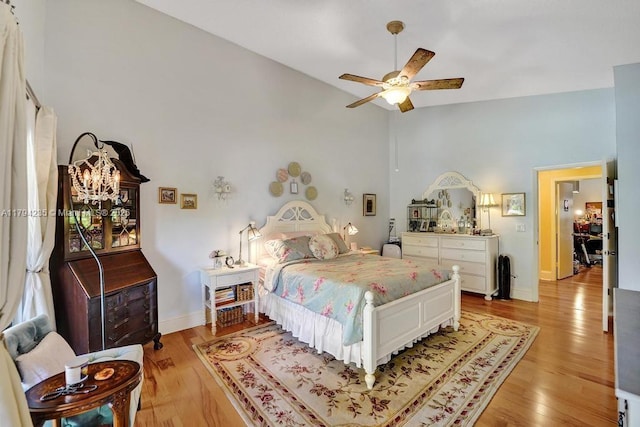 bedroom featuring ceiling fan, high vaulted ceiling, baseboards, and light wood-style flooring