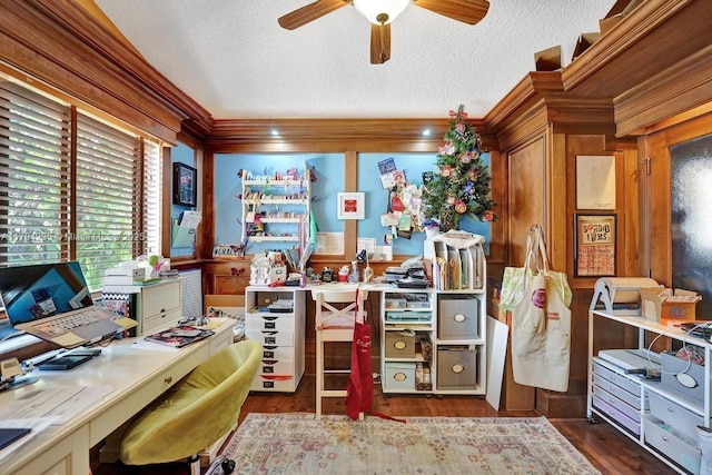 home office with crown molding, wood walls, wood finished floors, ceiling fan, and a textured ceiling