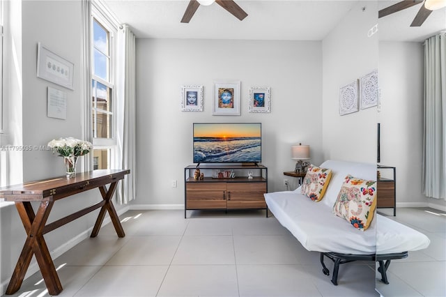 sitting room featuring ceiling fan, baseboards, and tile patterned floors