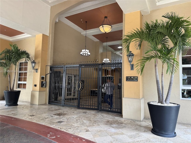 entrance to property with stucco siding, a gate, and fence