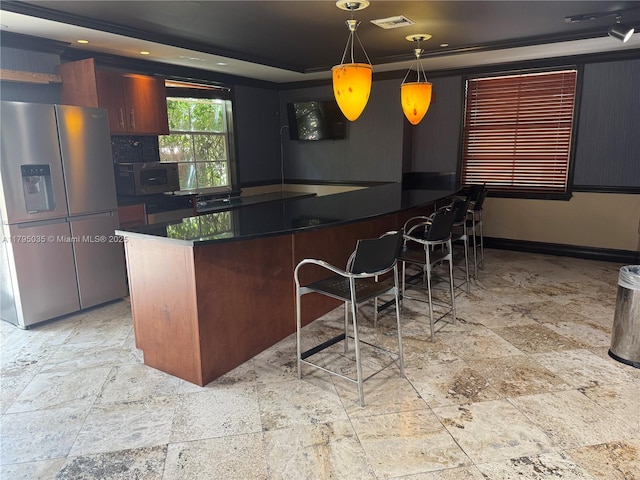 kitchen with a raised ceiling, dark countertops, stainless steel appliances, and stone tile floors