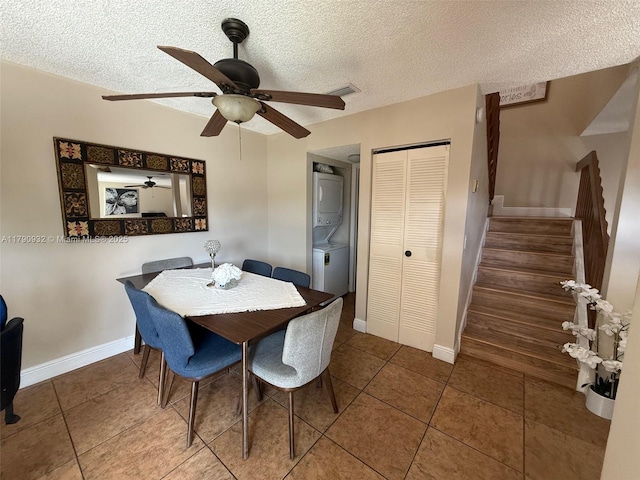 tiled dining space featuring stacked washer / drying machine, stairway, a textured ceiling, ceiling fan, and baseboards