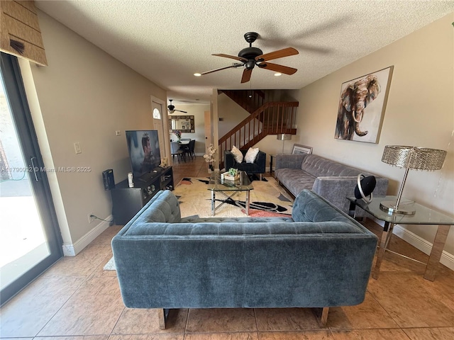 living room with ceiling fan, a textured ceiling, baseboards, stairs, and light tile patterned floors