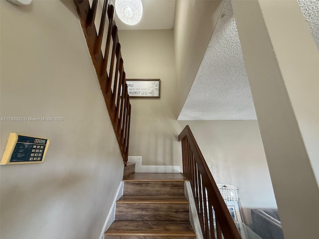stairs with wood finished floors, baseboards, and a chandelier