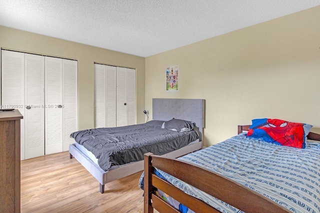 bedroom featuring two closets, wood finished floors, and a textured ceiling