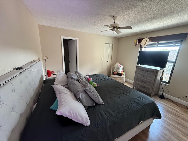 bedroom featuring wood finished floors, a textured ceiling, a ceiling fan, and baseboards