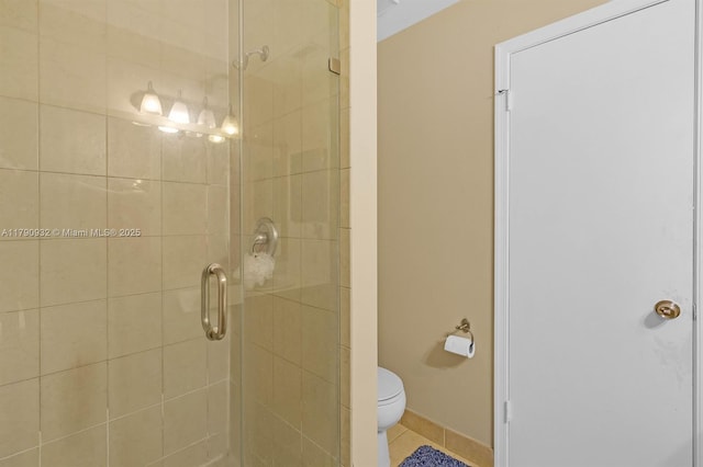 bathroom with a shower stall, toilet, and tile patterned floors
