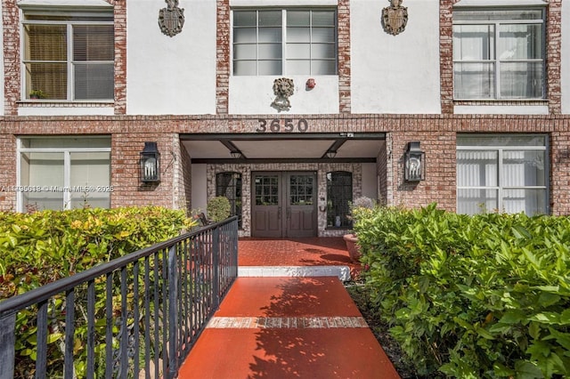 view of exterior entry featuring brick siding and stucco siding