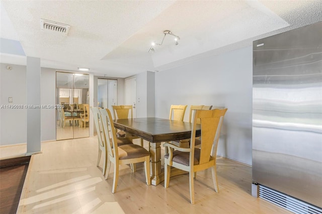 dining room with a textured ceiling, visible vents, and wood finished floors