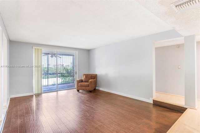 unfurnished room with baseboards, a textured ceiling, visible vents, and wood finished floors