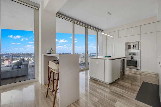 kitchen featuring white cabinets, light wood-style floors, modern cabinets, a kitchen island, and expansive windows