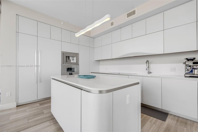 kitchen with white cabinets, stainless steel oven, and light wood-type flooring