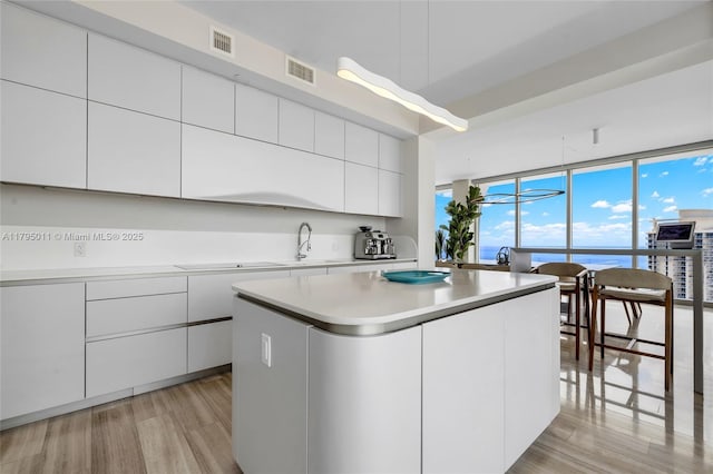 kitchen featuring modern cabinets, white cabinets, light wood-style flooring, and visible vents