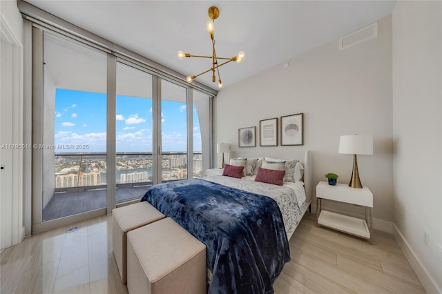 bedroom with a notable chandelier, baseboards, light wood-type flooring, visible vents, and expansive windows