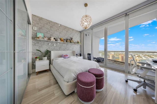 bedroom with an inviting chandelier, multiple windows, expansive windows, and light wood-style flooring