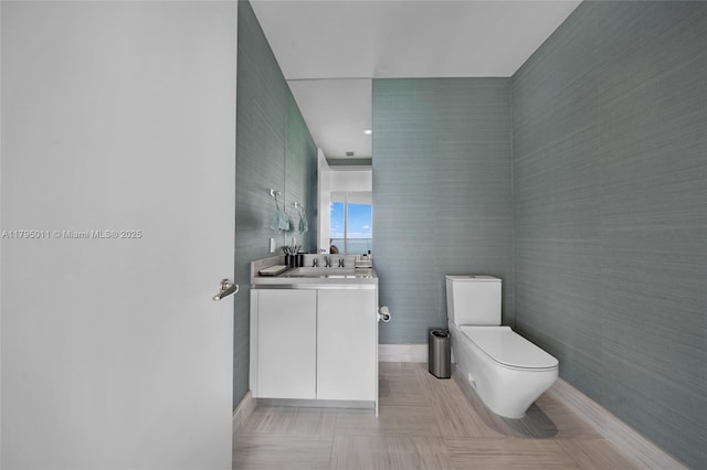 bathroom with baseboards, vanity, and toilet